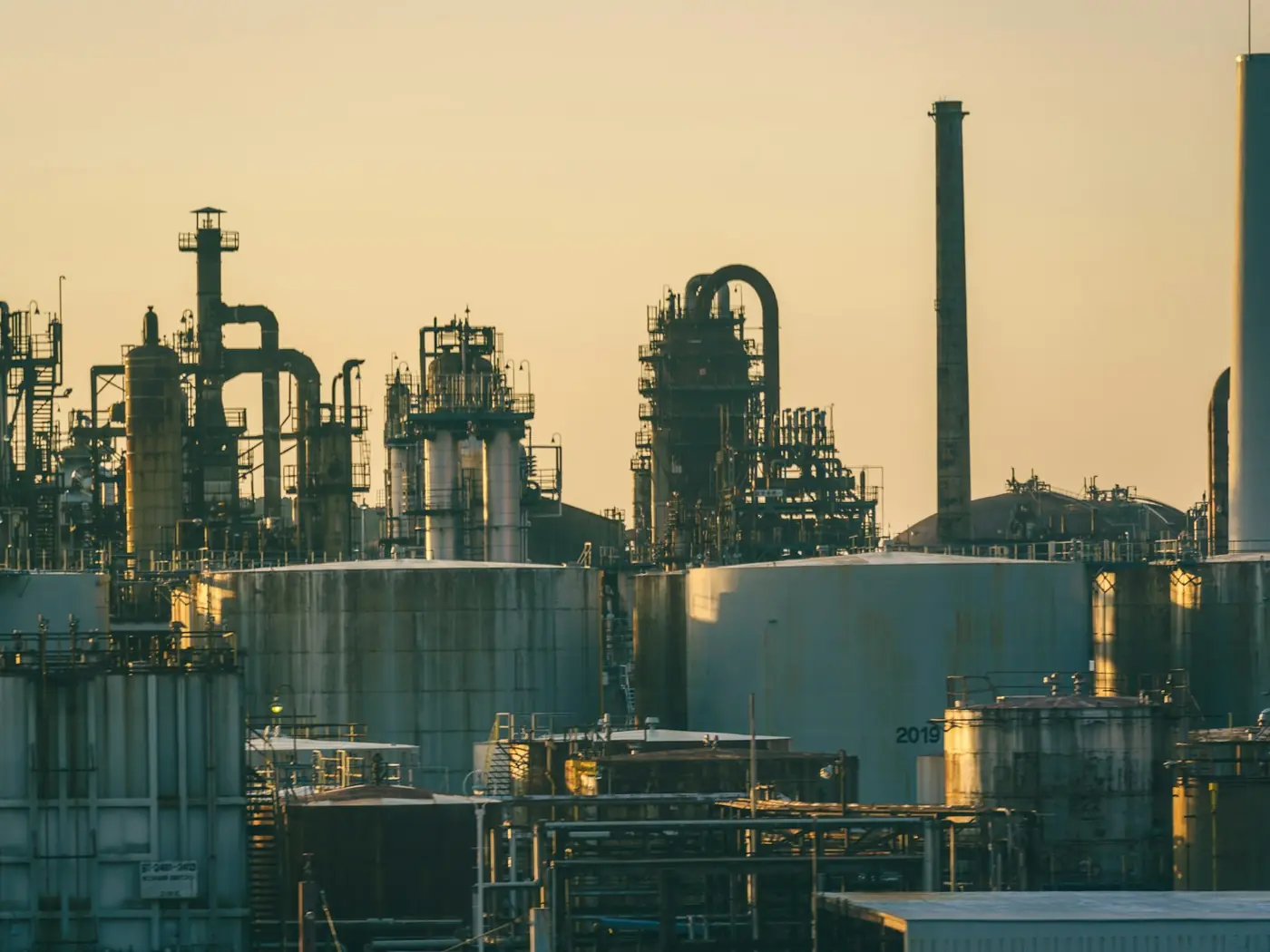 Refinery towers and stacks silhouetted in warm evening light