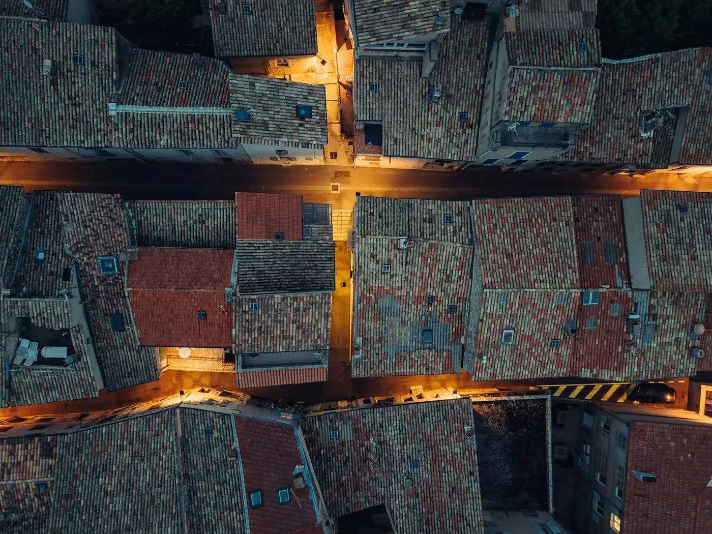 Overhead view of tiled rooftops in a dense town at golden hour