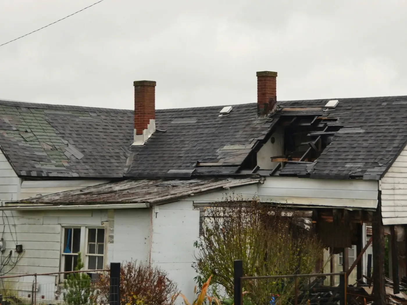 A weatherboard house with a collapsed and visibly damaged roof