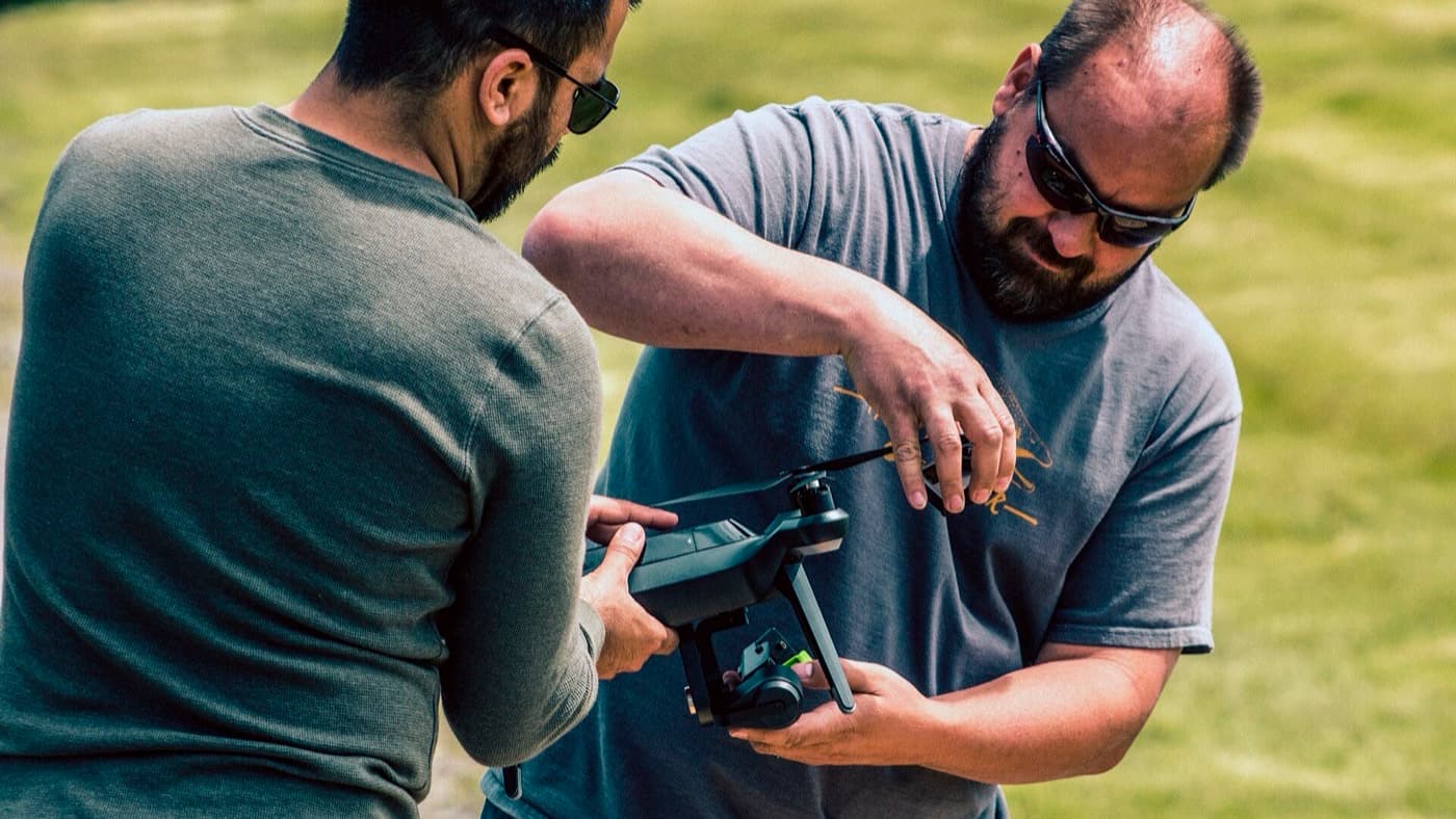 Two drone operators inspecting a quadcopter and its gimbal before a flight
