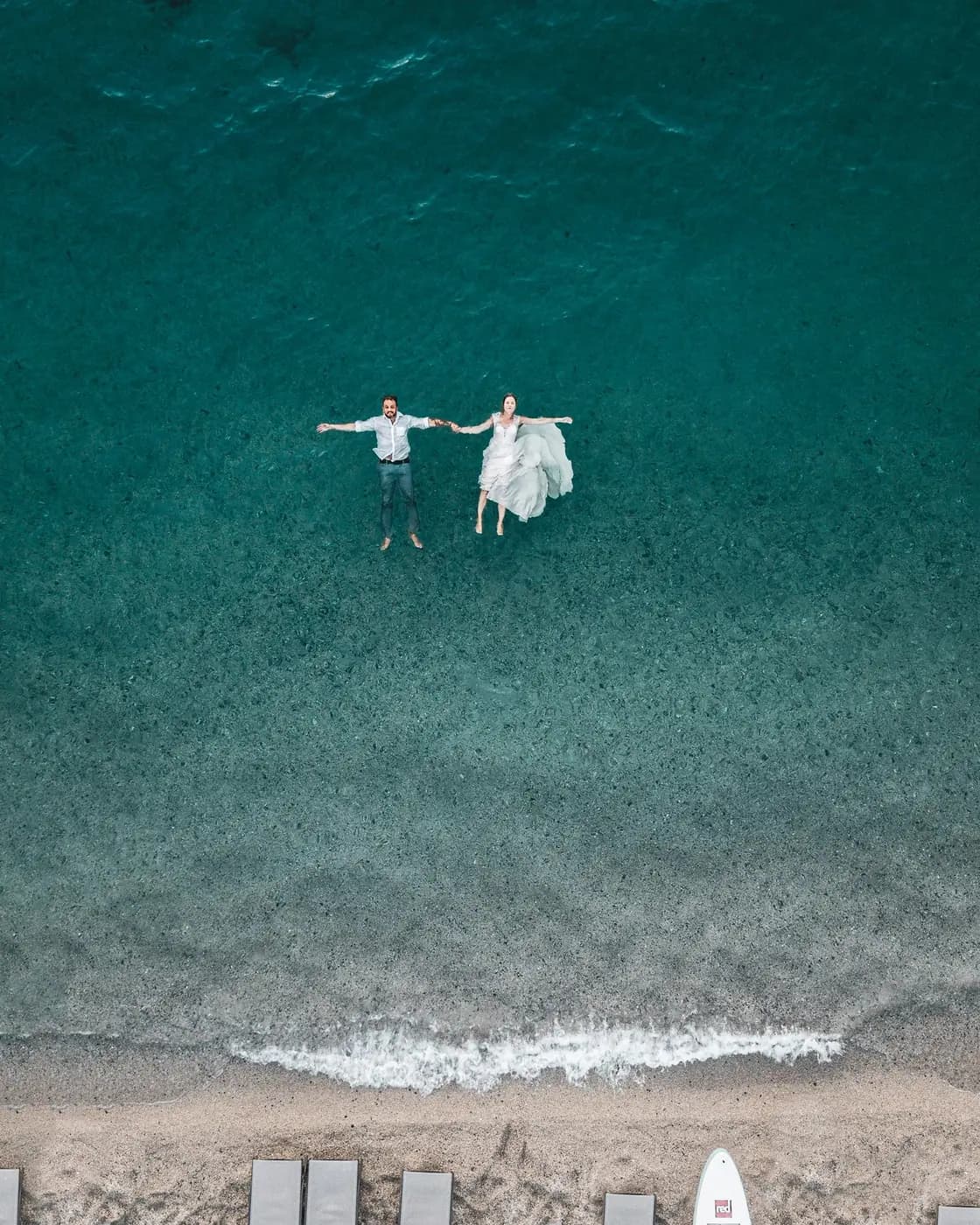 A couple floating in clear turquoise water, seen from above