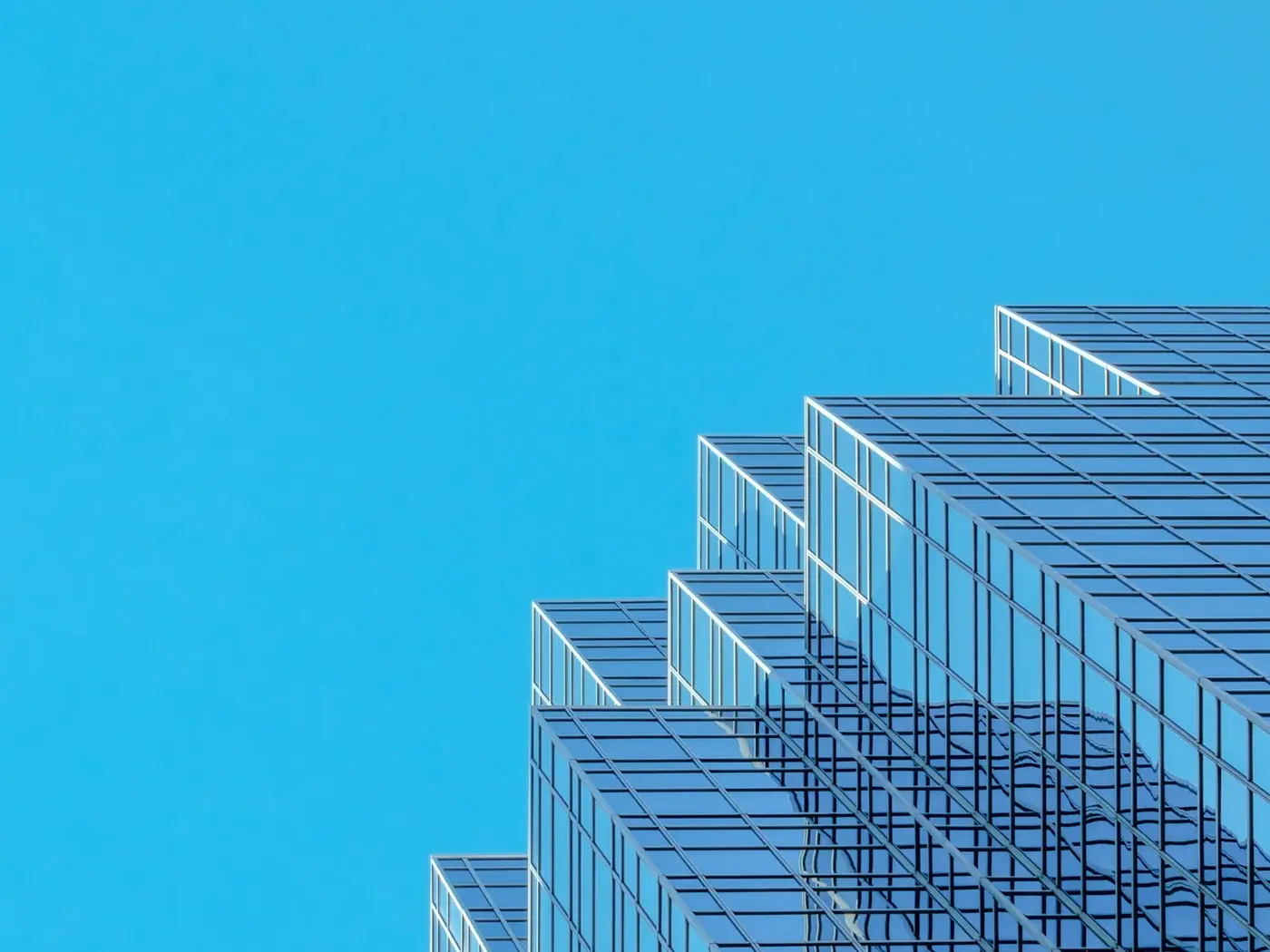 A stepped glass curtain-wall tower photographed against a clear sky