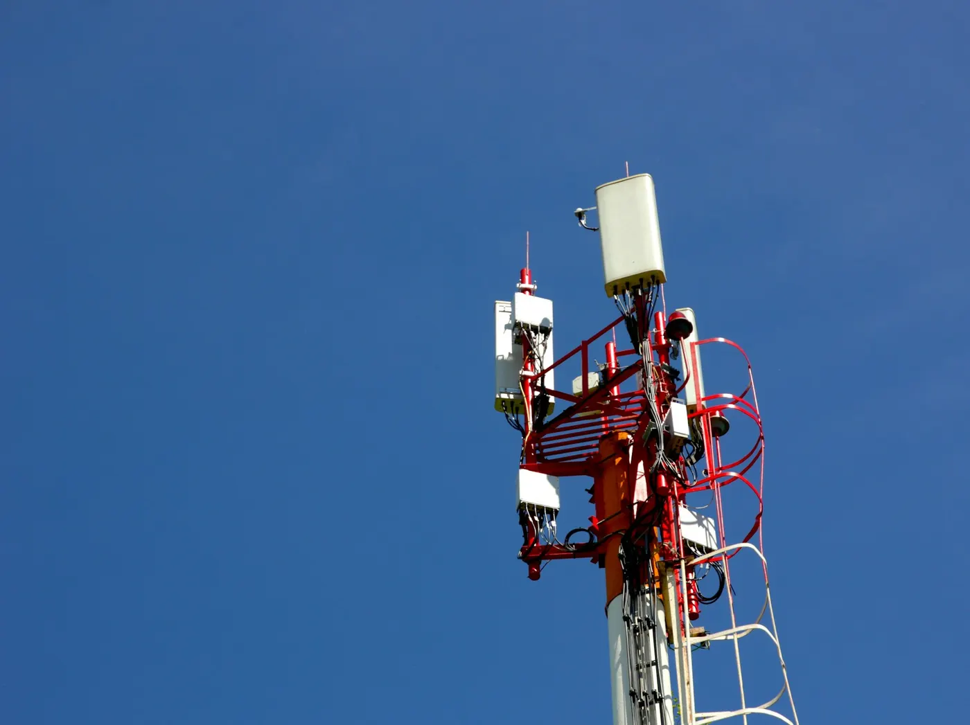 Pilon de telecomunicații roșu cu alb, cu antene, pe cer albastru
