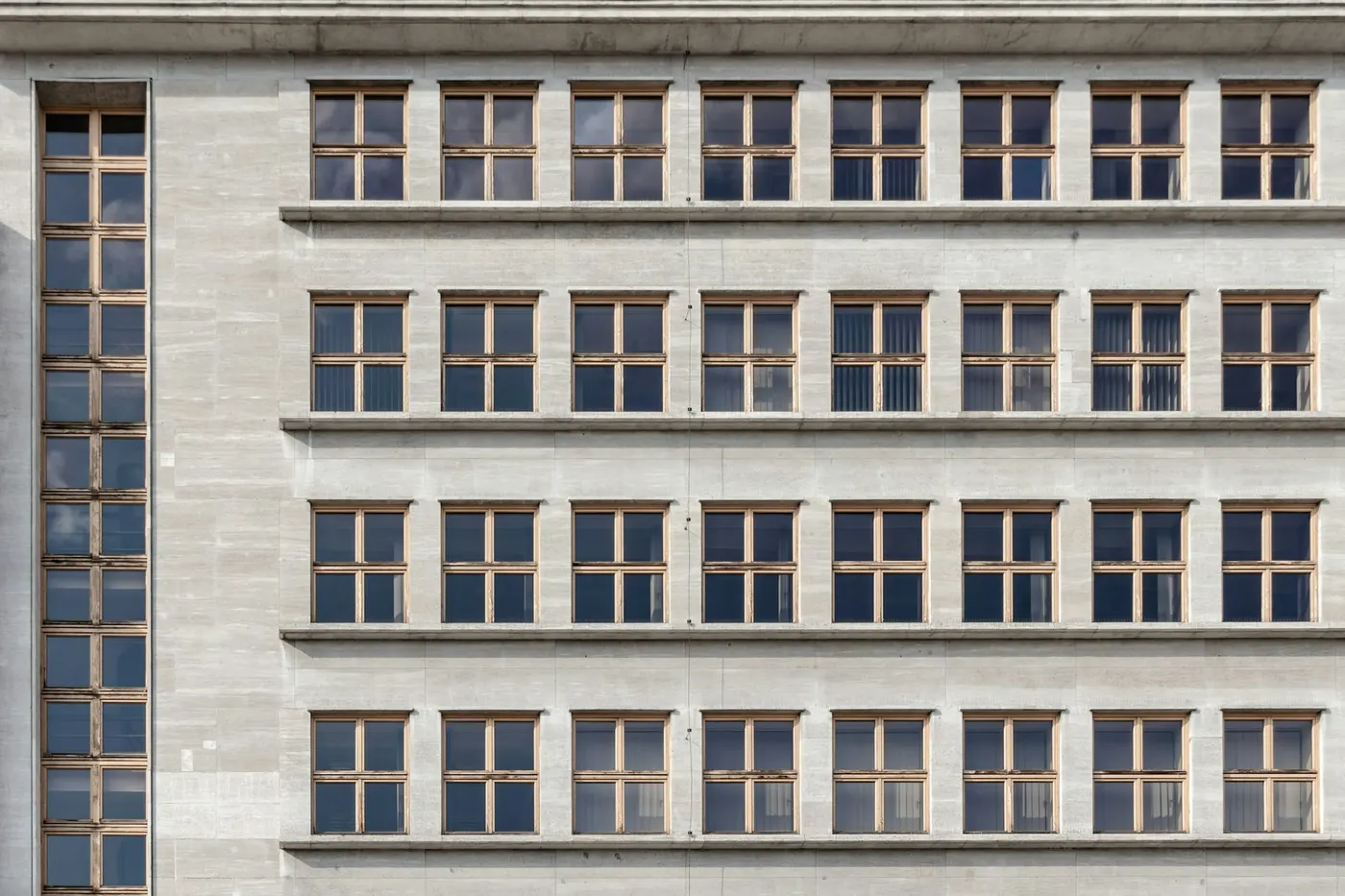 Stone facade of a multi-storey building with rows of windows