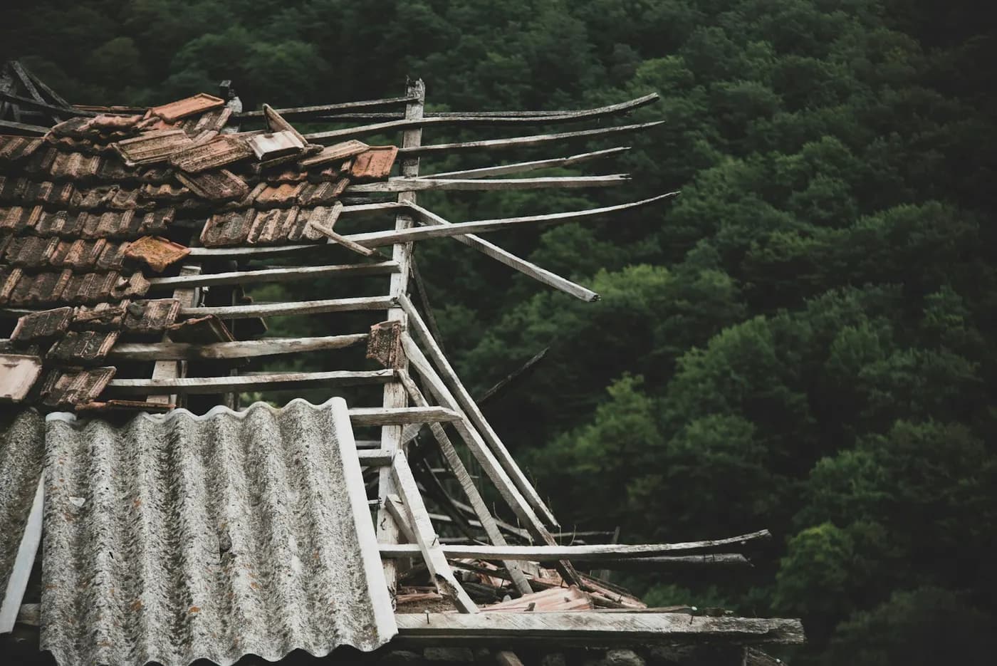 A tiled roof stripped to its battens, with a broken sheet below