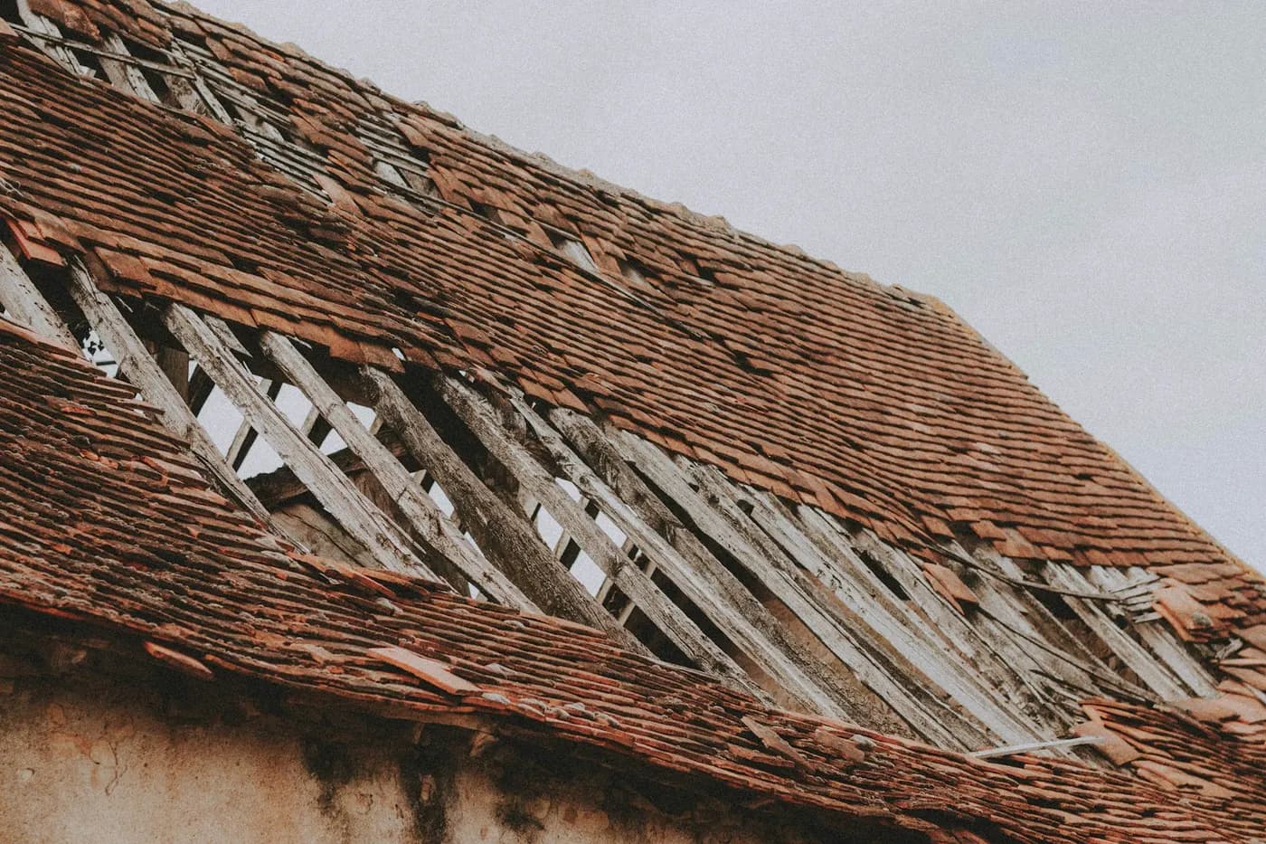 A tiled roof with broken battens and missing tiles