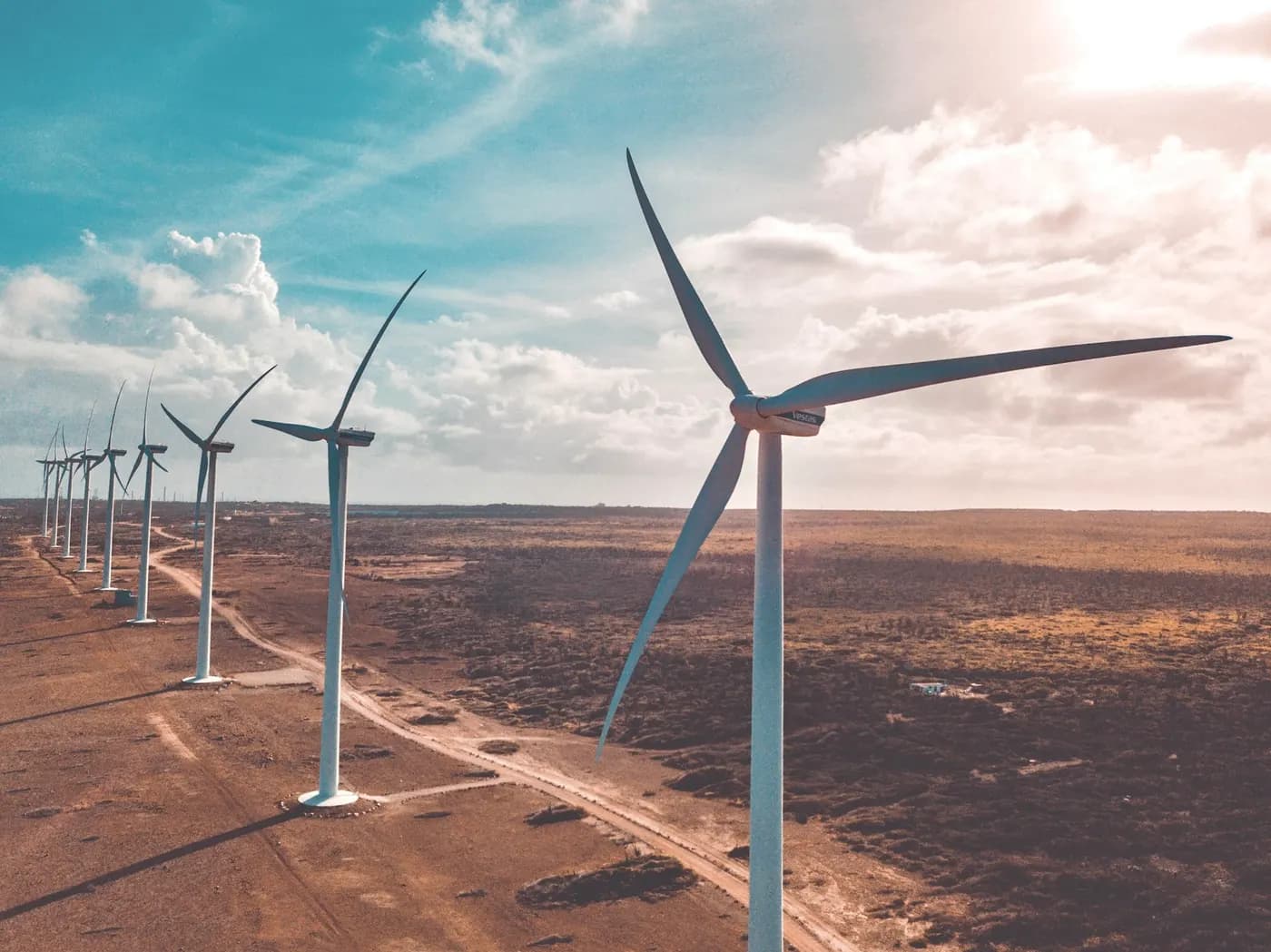 Un șir de turbine eoliene pe un teren arid, văzut din aer