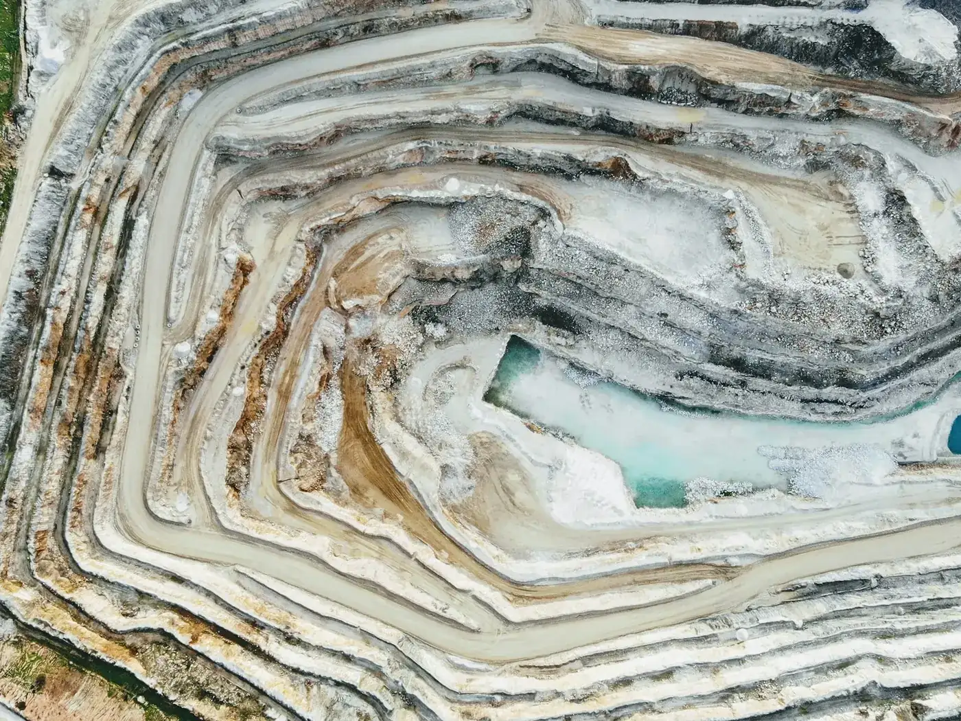 Overhead view of a terraced open-pit quarry with turquoise water